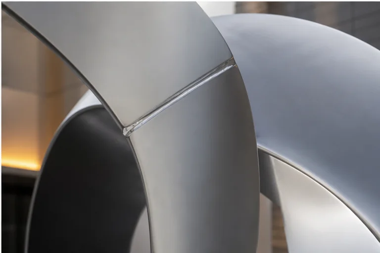 Close-up detail of polished and brushed stainless steel sculpture craftsmanship